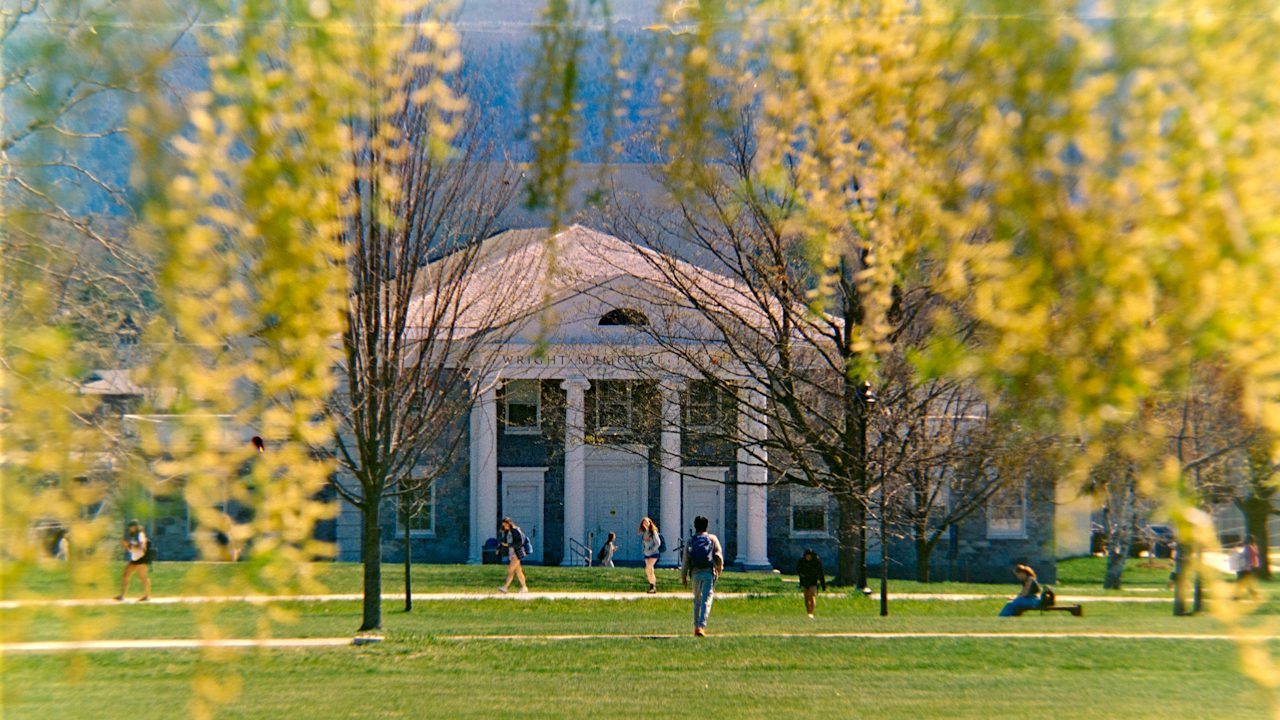 A campus building with columns on a tree-lined lawn