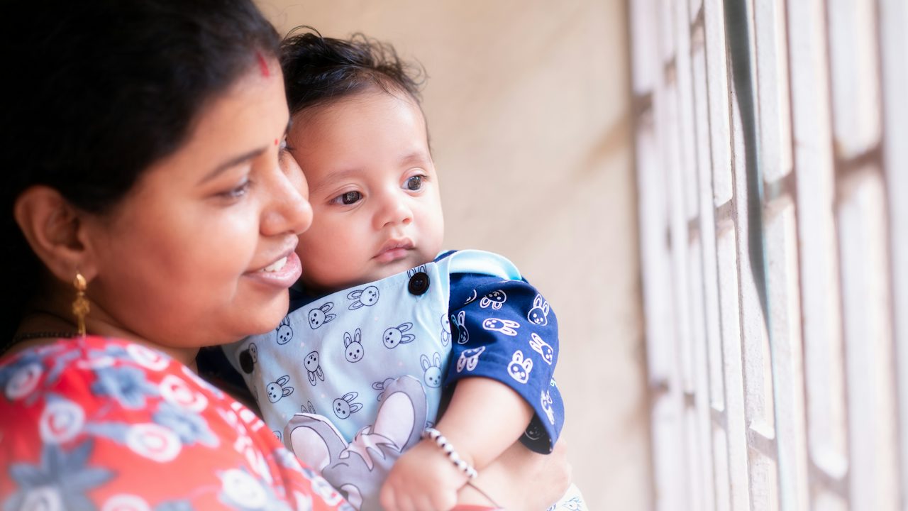 A woman holding a baby and looking out a window